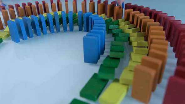 Line up of Dominoes in Rainbow Falling Colors with LGBT Colors of a Hand