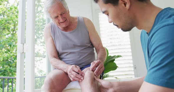 Retired senior man explaining about knee pain to physiotherapist at health club