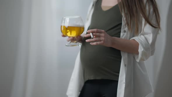 Unrecognizable Pregnant Woman with Cigarette and Beer Standing Indoors