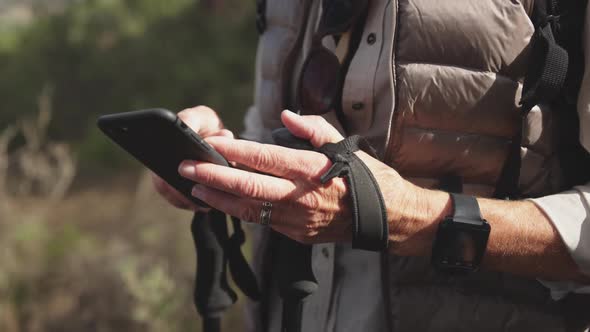 Close up view of senior woman holding smartphone in forest