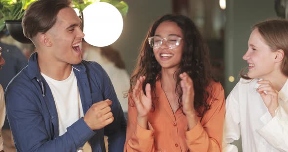 Pretty Girl in Glasses Talking, Smiling and Hugging Her Friends in Modern Cafe, Crop View 