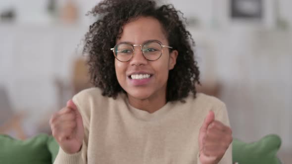 Portrait of Excited Young African Woman Celebrating at Home 