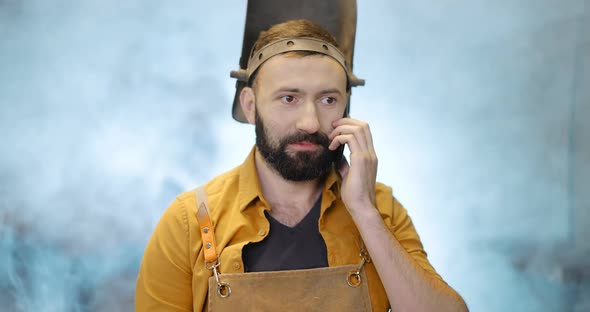 Welder with Phone at the Workshop