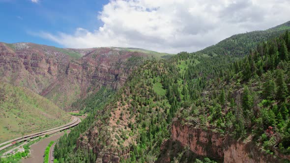 Aerial Drone Footage Flying Next To Beautiful Rocky Alpine Canyon Walls Covered In Healthy Green Fol