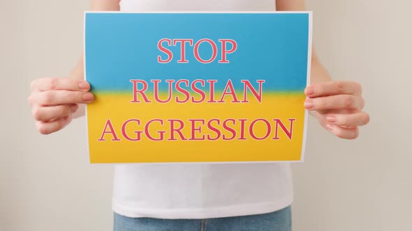 Hands is Holding a Poster with the Image of the Ukrainian Flag Which Says Stop Russian Aggression