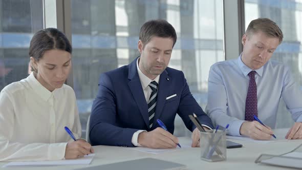 Executive Business People Writing Documents and Talking on Office Table