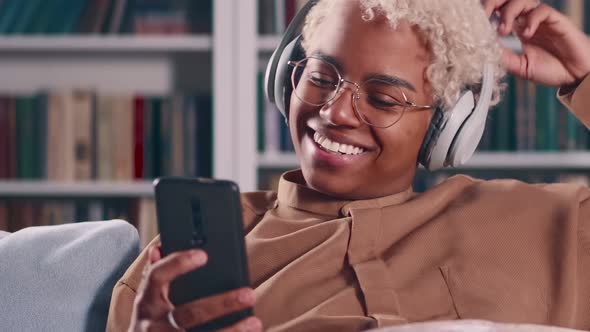 Young African American Woman in Headphones Makes Video Call in Mobile Phone