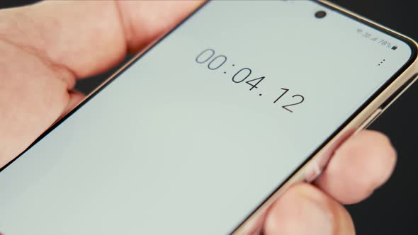 Close up of smartphone with digital stopwatch or timer on the screen.