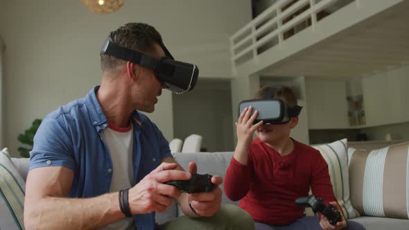 Caucasian father with son using vr headsets and sitting in living room