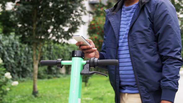 Man with Smartphone Riding Electric Scooter