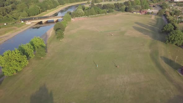 Aerial view, people in field playing with dog as train passes by in background at golden hour