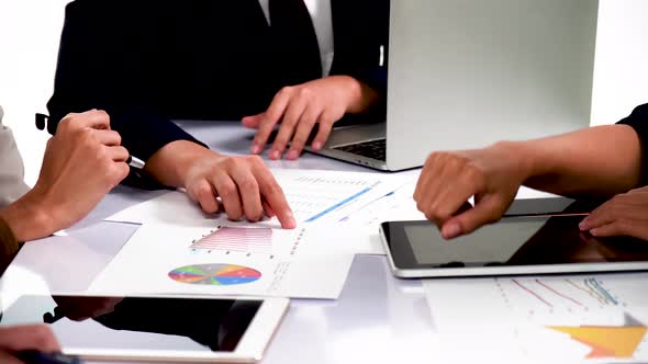 Businessmen and women analyze paperwork talk work together gather at briefing table share ideas 