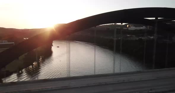 Side pan drone shot of the 360 bridge in Austin Texas, with the Hill Country in the background