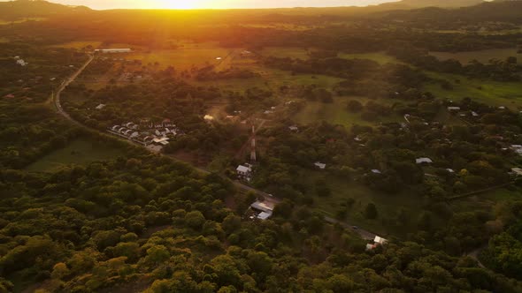 Aerial view of a pompous mansion towering above small communes within the jungle of Costa Rica. Ligh