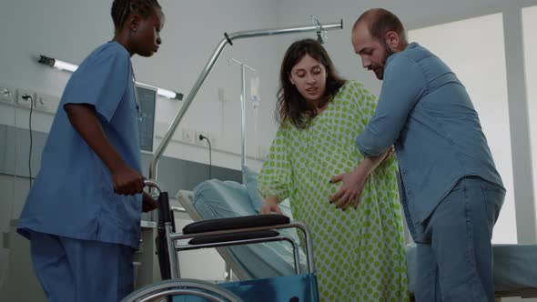 Caucasian Man Helping Pregnant Woman in Hospital Ward