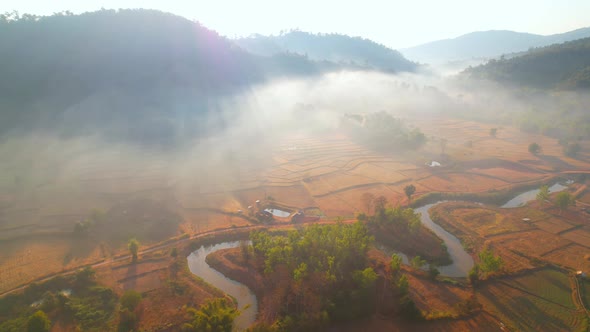 Aerial view over villages and barren fields in countryside during sunrise