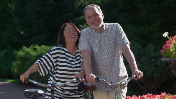 Happy Senior Couple with Bikes Having Fun at City Park