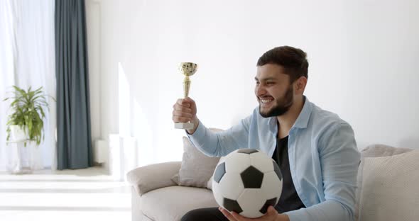 A Young Indian Football Fan is Watching TV at Home