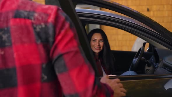 Smiling Man with Well-Groomed Beard Opening the Car Door for His Stunning Joyful Wife