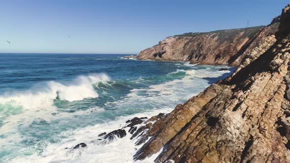 Aerial - Flying from rocky coastline over heavy waves crashing into sheer cliffs, The Point Mossel B