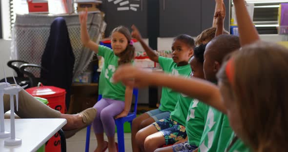 Side view of mixed-race schoolkids raising their hands in the classroom 4k