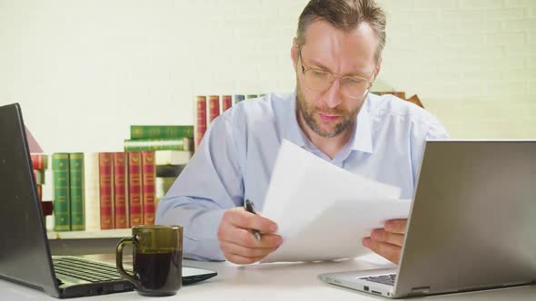 A Man at the Workplace in the Office Checks Documents