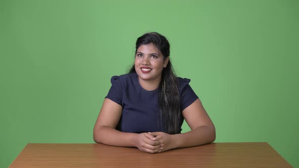 Young Overweight Beautiful Indian Businesswoman Against Green Background