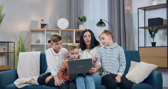 Mother Explaining How to Use Laptop Her three Interested Different Ages Sons