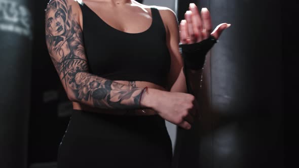Tattooed Woman in Sports Top Binding Her Hands Before Box Training