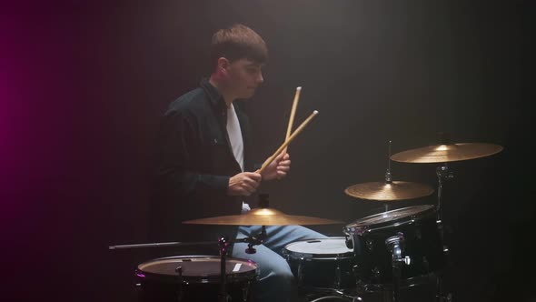 Drummer Playing the Drum Set in a Dark Room on a Black Background