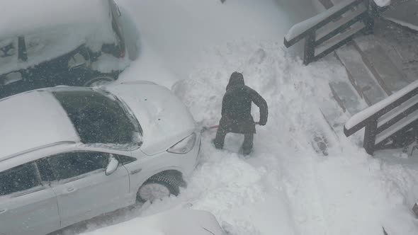 Top View As a Man Clears a Car Parked Near the Snow