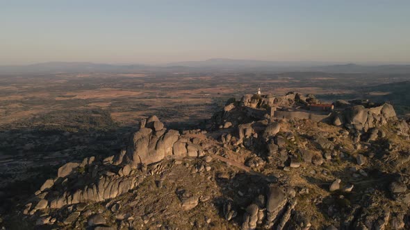 Monsanto castle and surrounding landscape at sunrise, Portugal. Aerial backward