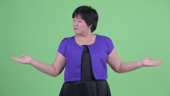 Happy Young Overweight Asian Woman Comparing Something