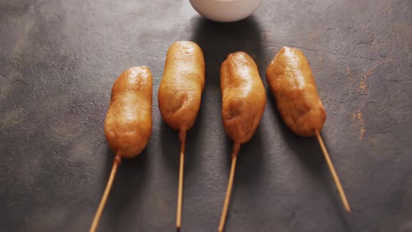 Video of corn dogs with dip on a black surface