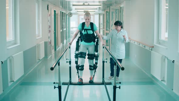 A Woman in the Exosuit is Doing Physiotherapy with a Doctor