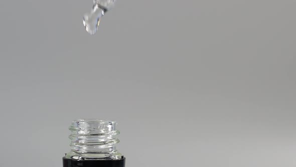Dripping cosmetic oil from a pipette into a bottle. 