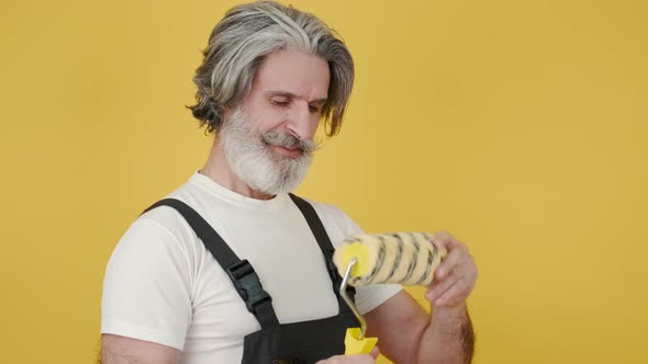 Worker Holding Paint Brush and Smiling on Yellow Background