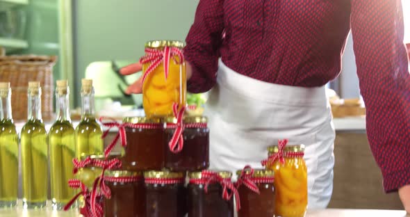 Female staff showing jars of preserves and olive oil on counter