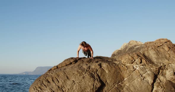 Young boy does push ups workout on the rocks