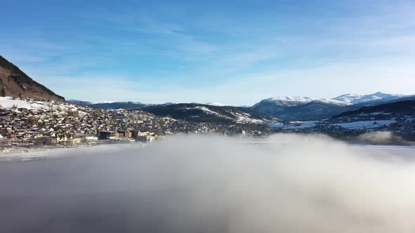 Voss morning aerial flying through frost haze above Vangsvatnet lake while looking at town of Voss w