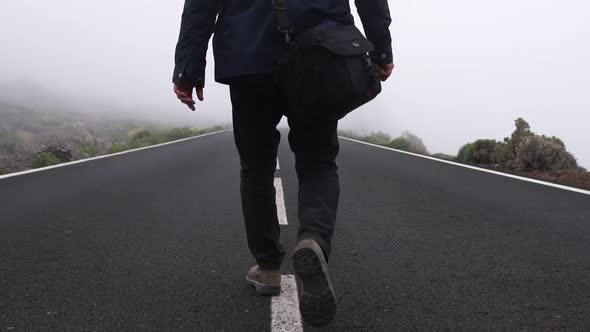 Man Walking Down Middle Of Empty And Misty Road