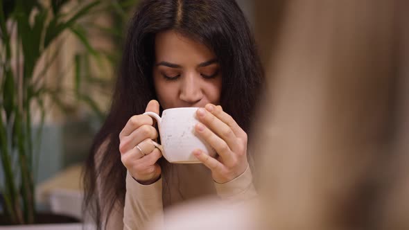 Portrait of Attractive Middle Eastern Young Woman Smelling Tasting Hot Tasty Tea Sitting in Cafe