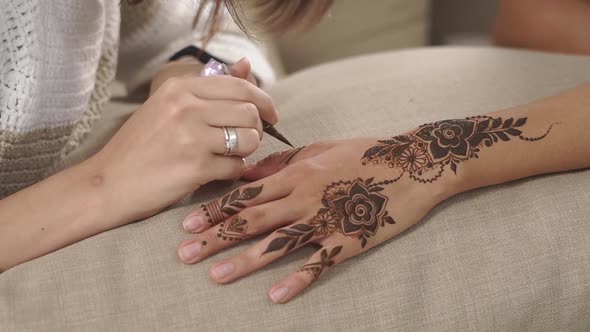 Woman Is Drawing Mehndi Designs on Hands of Her Friend Girl, Close-up