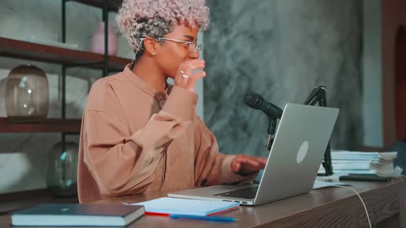 Young African American Woman with Smile Waving Hands Sits at Table with Laptop