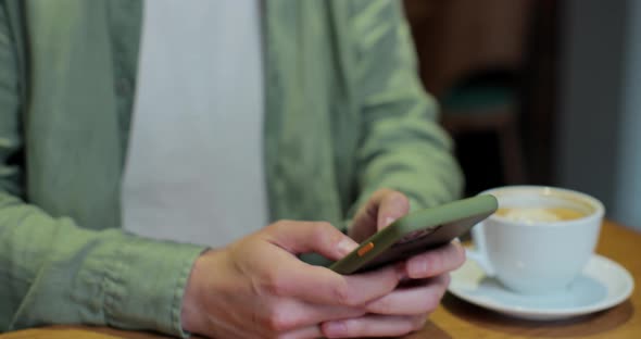 Close Up of Businessman at Cafe Sitting on a Table Reading Phone Message or Downloading an App for