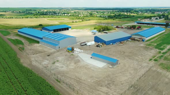 Warehouses with Blue Roofs Among the Wheat Fields