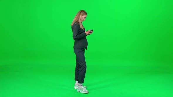 Businesswoman in a Suit Standing on Chroma Key Background Woman Using Smartphone Texting and Surfing