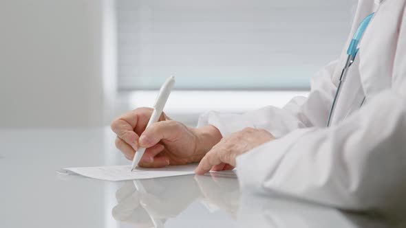 Senior female doctor writes medicine prescription on paper sheet