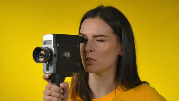 A Beautiful Darkhaired Woman Cinematographer is Using a Retro Camcorder