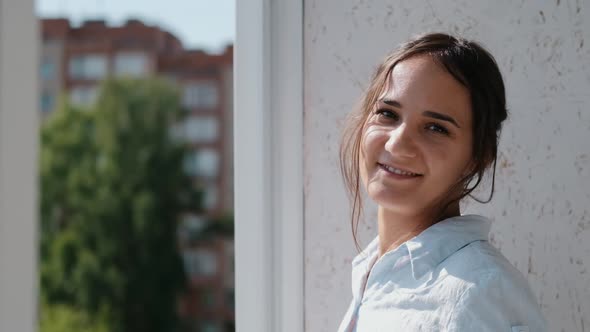 Young Woman Standing on the Balcony Smiling and Looking at the Camera